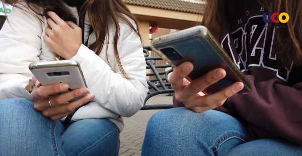 Dos adolescentes consultan su teléfono móvil